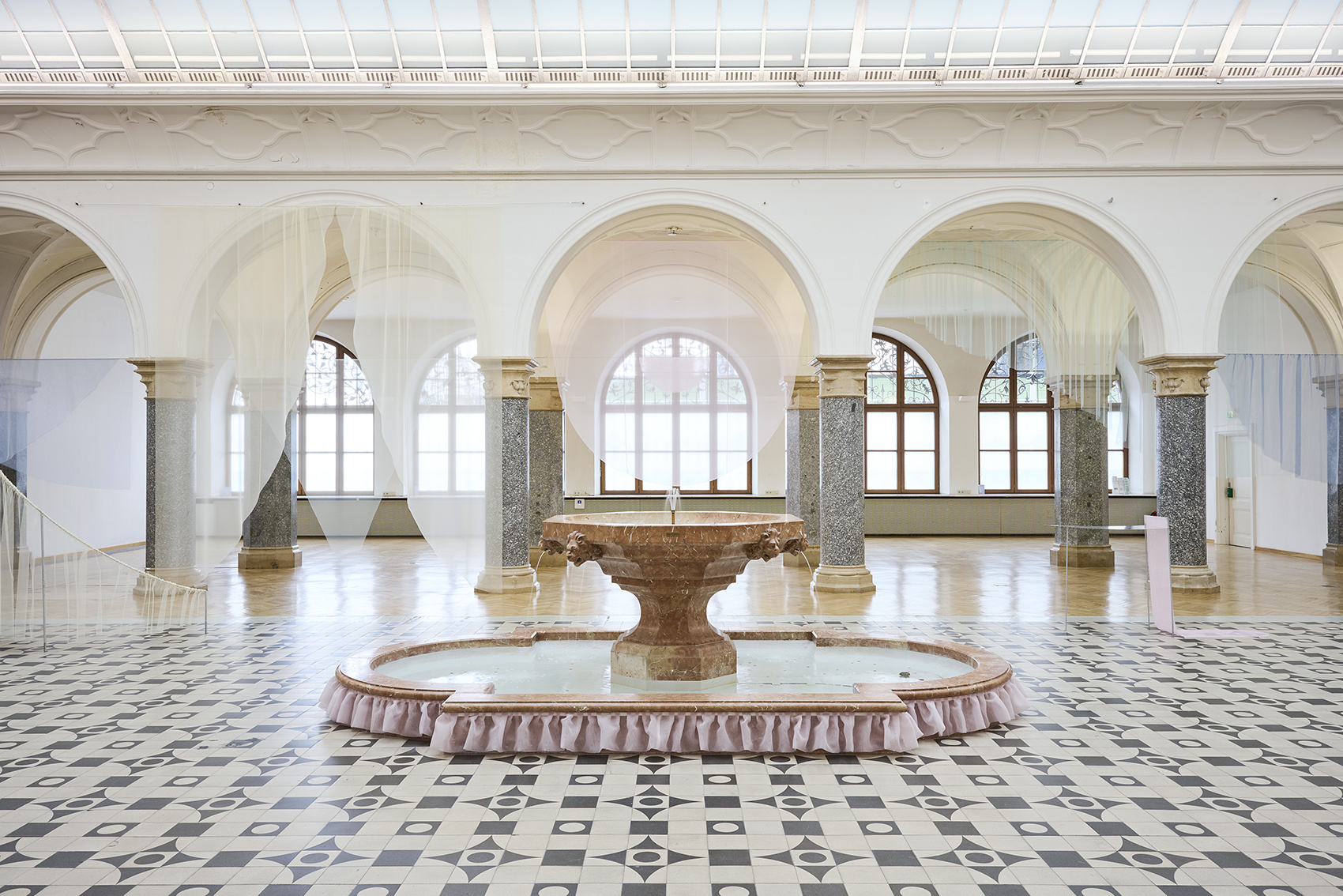 zu sehen ist der Brunnen in der Rathausgalerie, darum hängen vorhangartige Stoffbanner